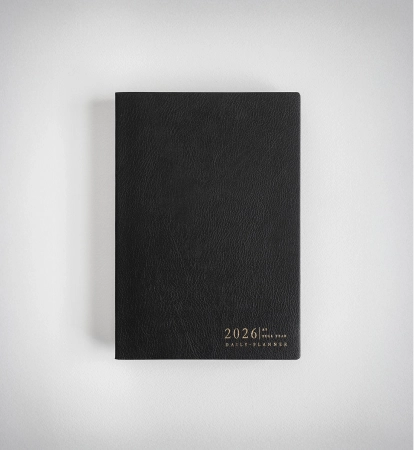Black 2026 daily planner with gold embossed text on the bottom right corner, placed on a white surface.